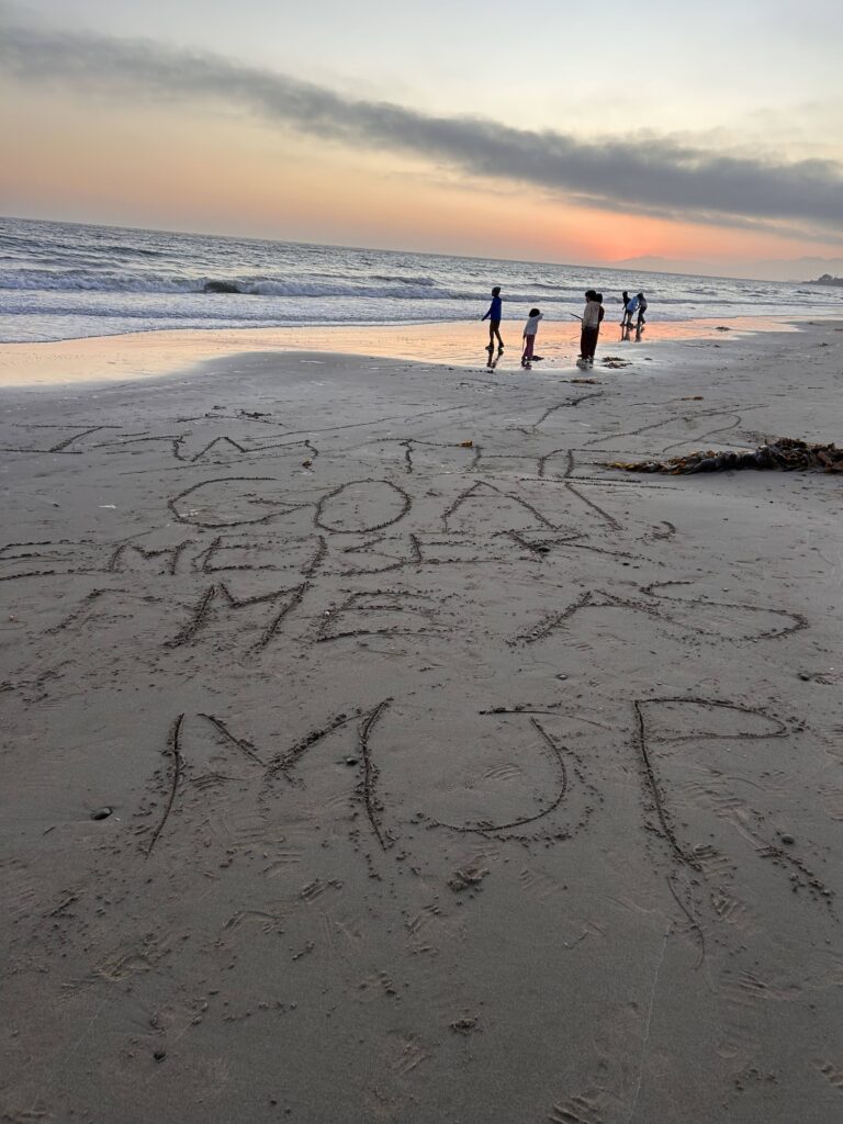 A photo of some messages written in the sands of the Ventura beach, one of which reads "I am the GOAT"